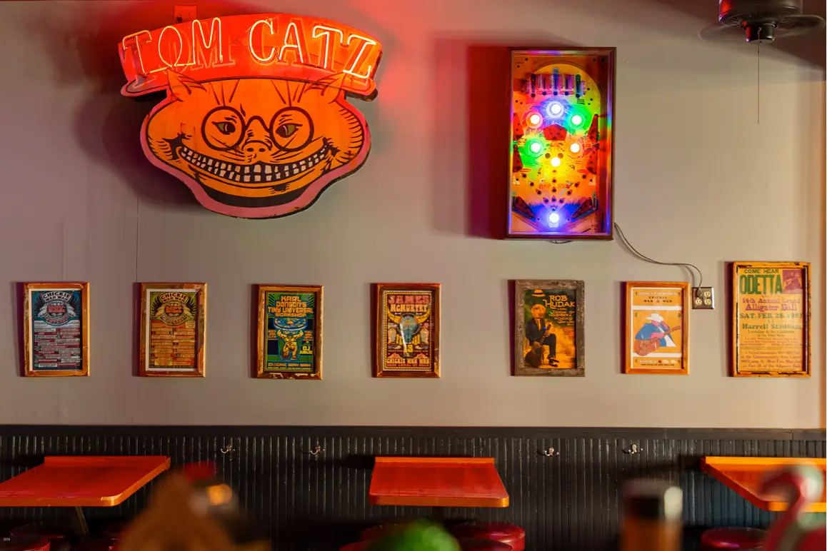 The Tom Catz neon sign and vintage concert-poster wall inside Chickie Wah Wah