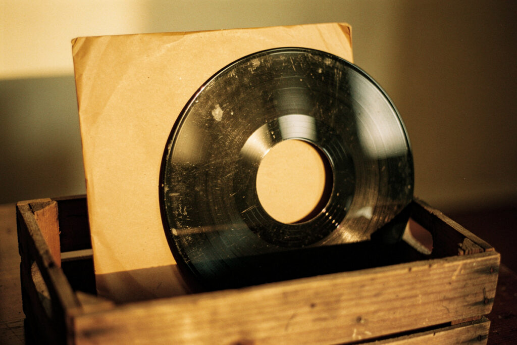 A vintage 45 RPM vinyl record and its paper sleeve in a wooden crate, evoking the 1950s New Orleans rhythm and blues era