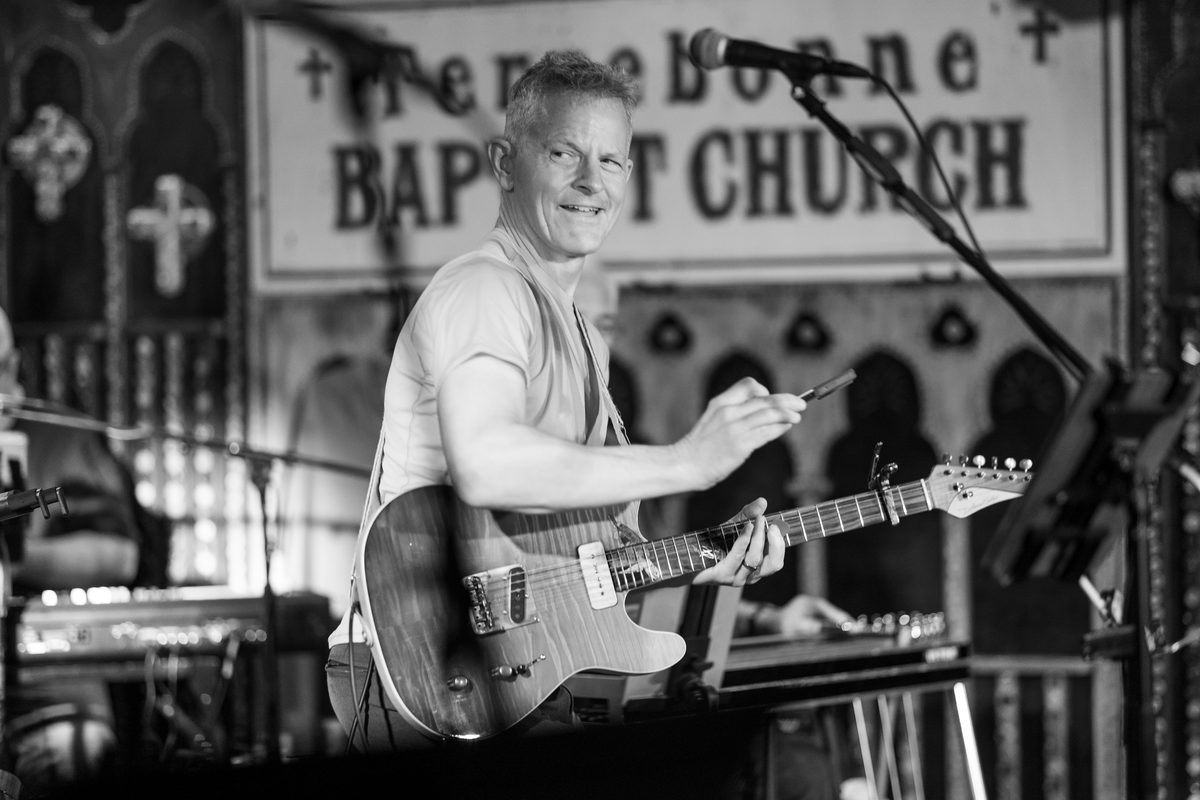 A musician performs on the Chickie Wah Wah stage in front of a vintage Terrebonne Baptist Church sign, one of the signs from shuttered New Orleans buildings that Dale Triguero collected for the walls